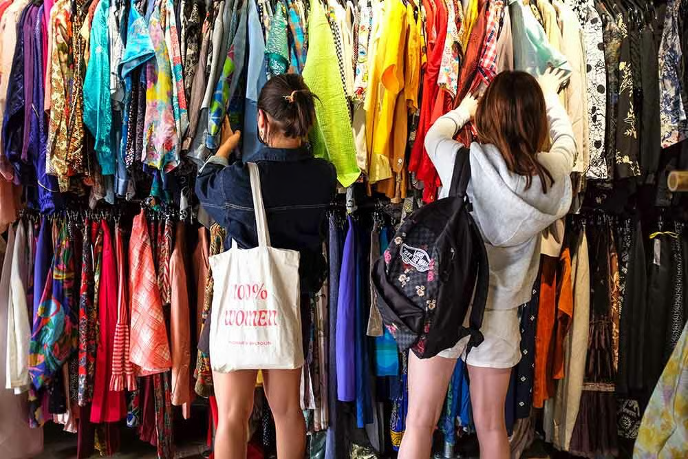 Mujeres buscando prendas en una tienda de ropa de segunda mano